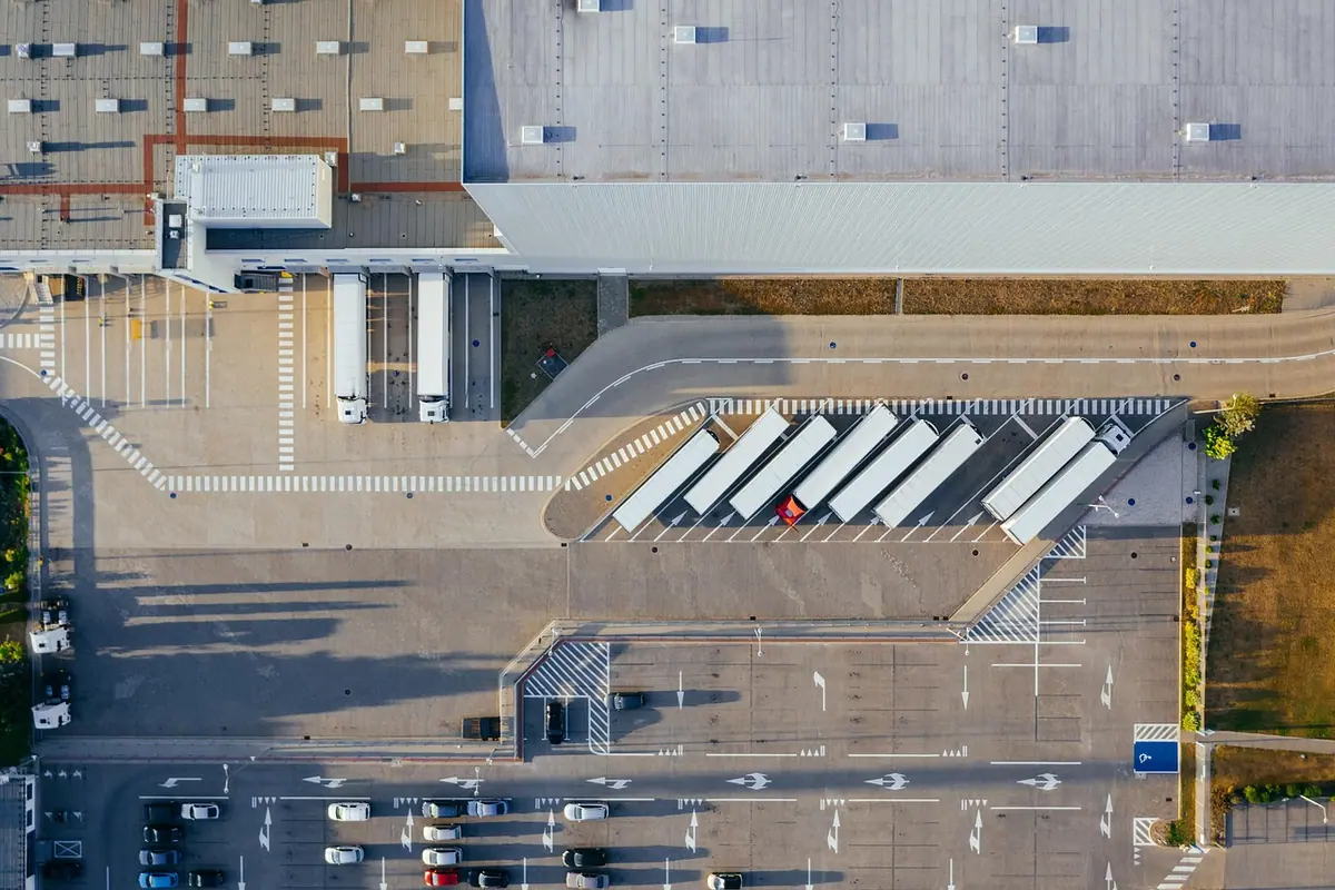 Vedere de sus a unui centru logistic cu camioane la rampe, pentru livrări între state membre