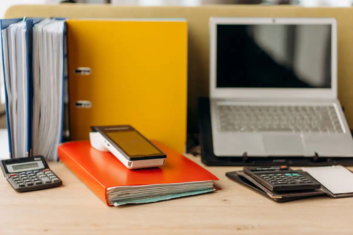 Bibliorafturi colorate, laptop și calculator pe birou, pregătite pentru cererea de certificat de atestare fiscală