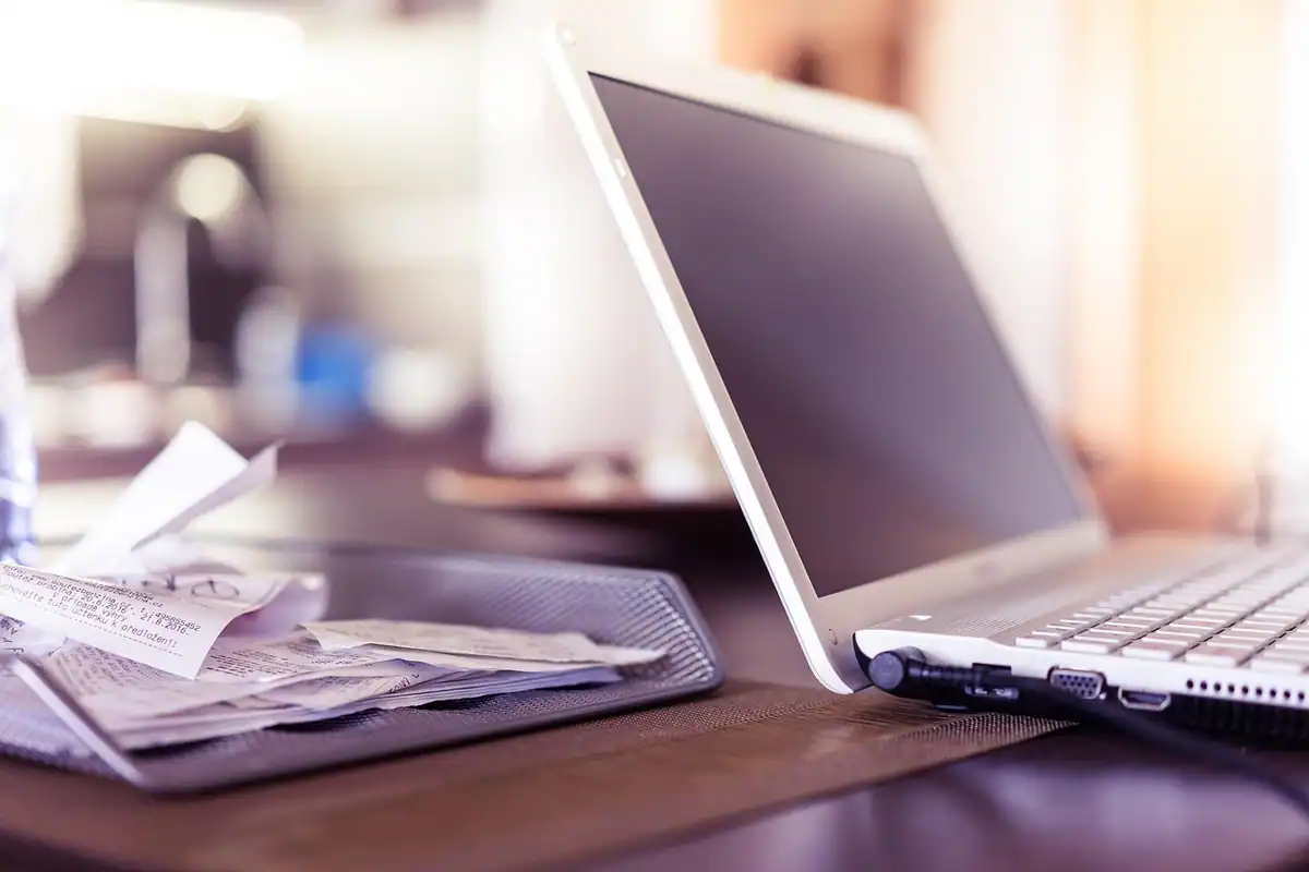 Birou cu laptop, foldere sortate și bonuri fiscale împrăștiate, la clasificarea cheltuielilor deductibile