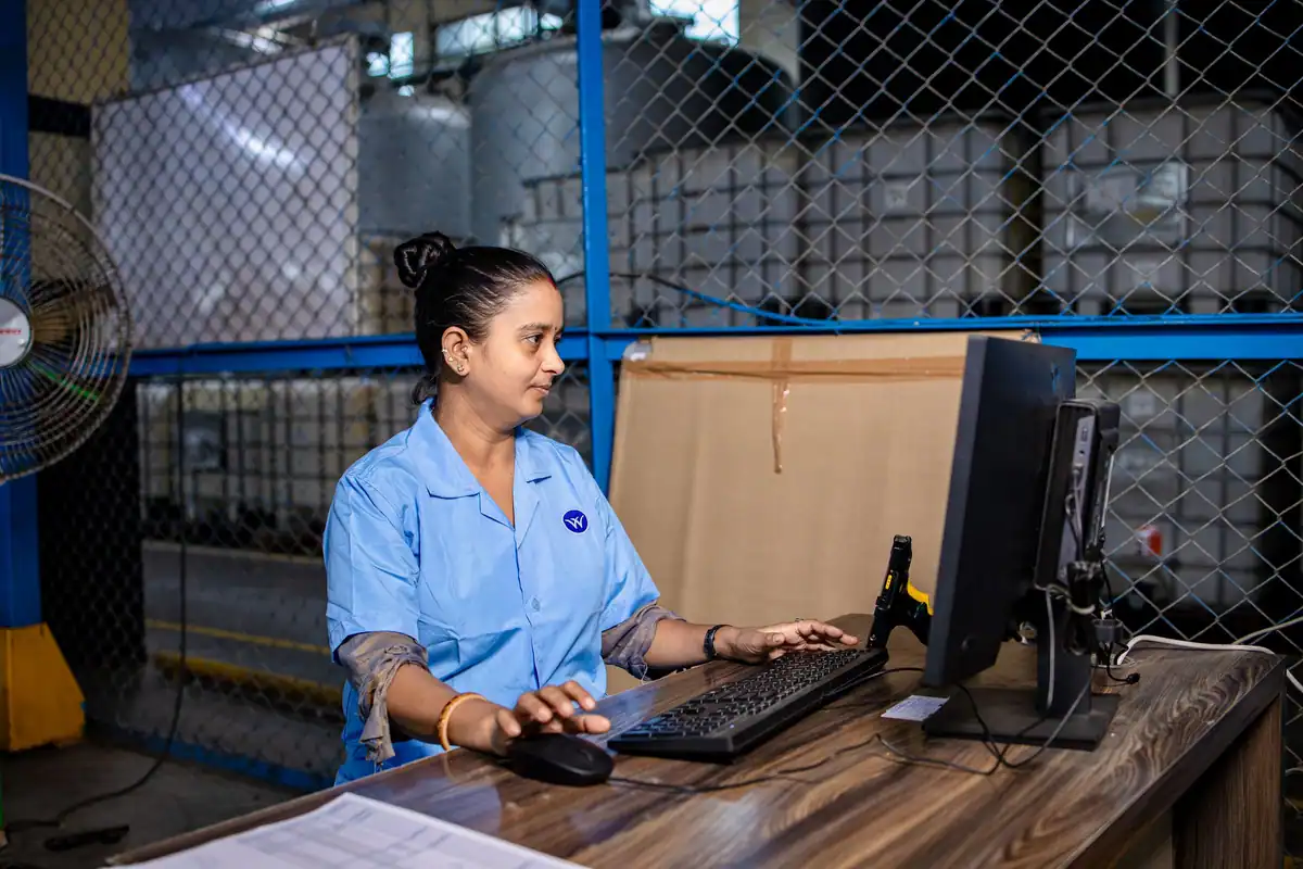 Femeie care lucrează la calculator într-un spațiu industrial, la o fabrică
