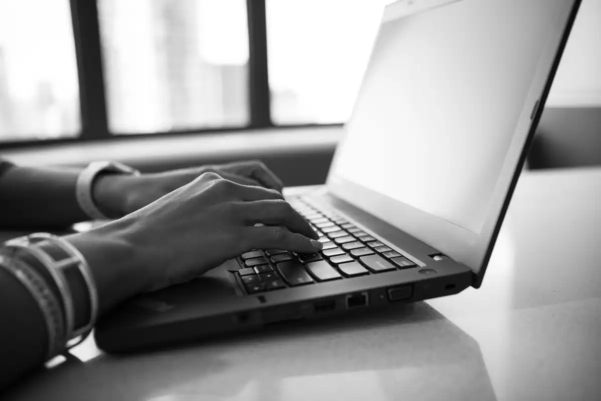 Mâini pe tastatura unui laptop, într-o fotografie alb-negru, în timpul validării facturii înainte de trimitere