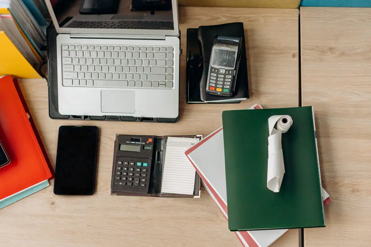 Birou cu laptop, terminal de plată, calculator și documente, la verificarea condițiilor de deducere a TVA