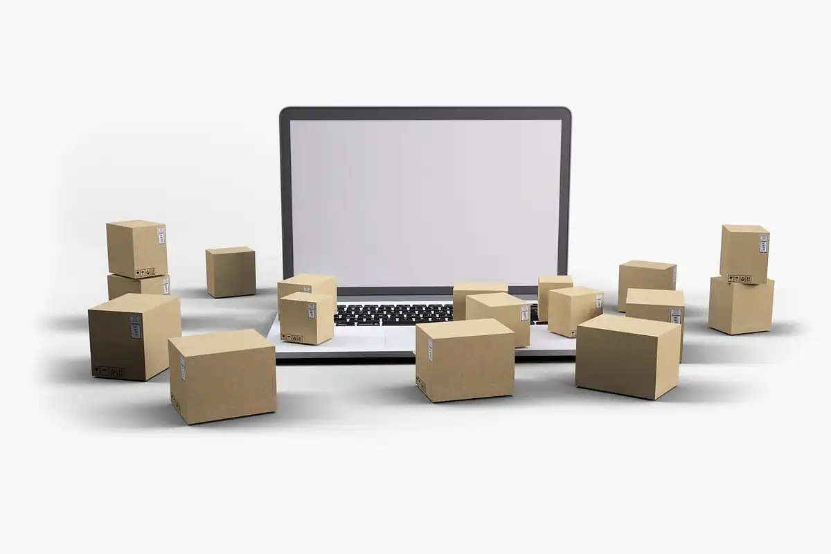 Colete din carton așezate în jurul unui laptop, simbol al vânzărilor online facturate către persoane fizice