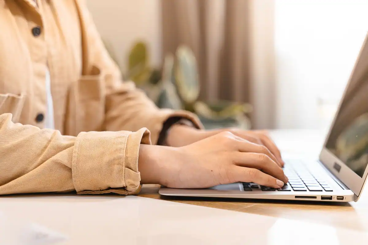Femeie care tastează pe laptop, cu mâinile pe tastatură, la emiterea facturilor electronice prin e-Factura