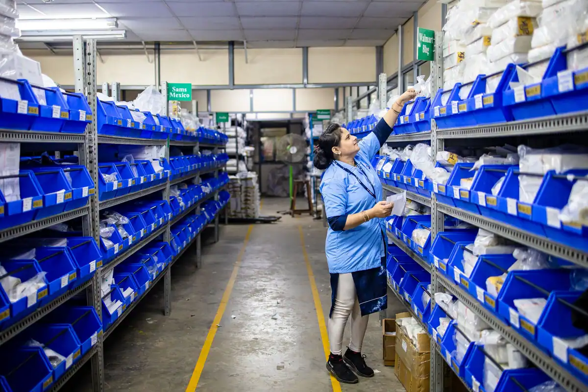 Angajată în uniformă albastră care numără produse pe rafturile unui depozit, la inventarierea anuală