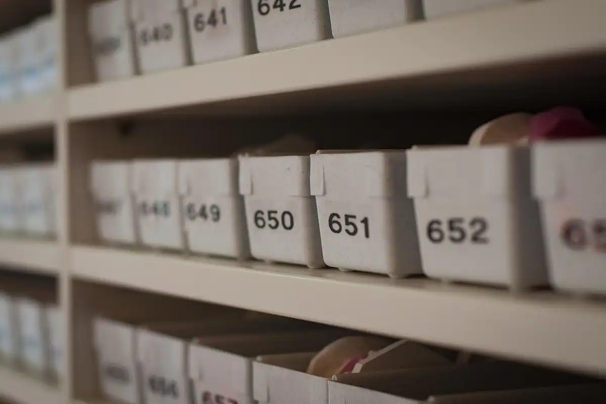 Cutii numerotate pe rafturi de depozit, cu etichete vizibile, pentru inventarierea patrimoniului firmei
