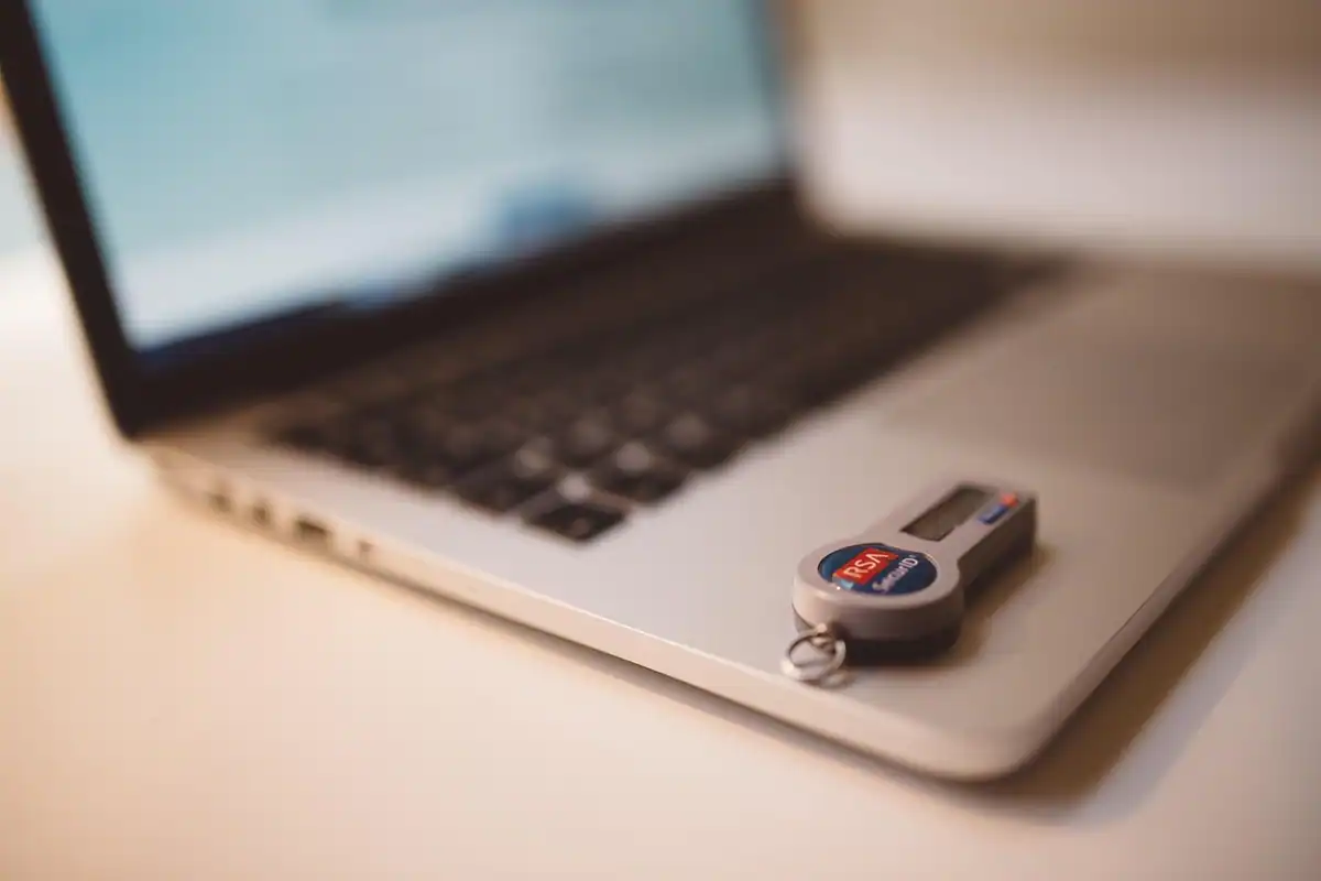 Cheie de securitate USB atârnată lângă un laptop deschis, folosită pentru accesul firmei în SPV